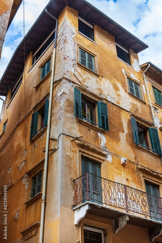 Colored facades of old buildings with balconies decorated with plants in the old part of Verona. Traditional Italian buildings