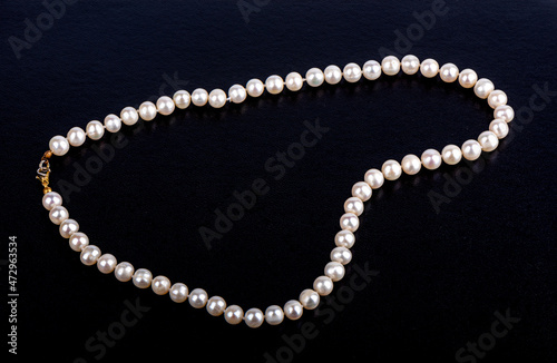 Pearl beads on a dark leatherette surface with space for text.