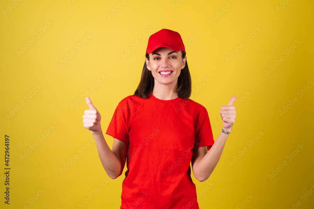 Delivery service worker woman in red cap, blank t-shirt, uniform, work clothes, courier at the service during quarantine, coronavirus covid-19 virus shows thumbs up Delivery service worker woman in red cap, blank t-shirt, uniform, work clothes, courier at the service during quarantine, coronavirus covid-19 virus shows thumbs up
