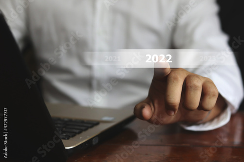 Business man touching screen with 2022 writing on virtual screen.