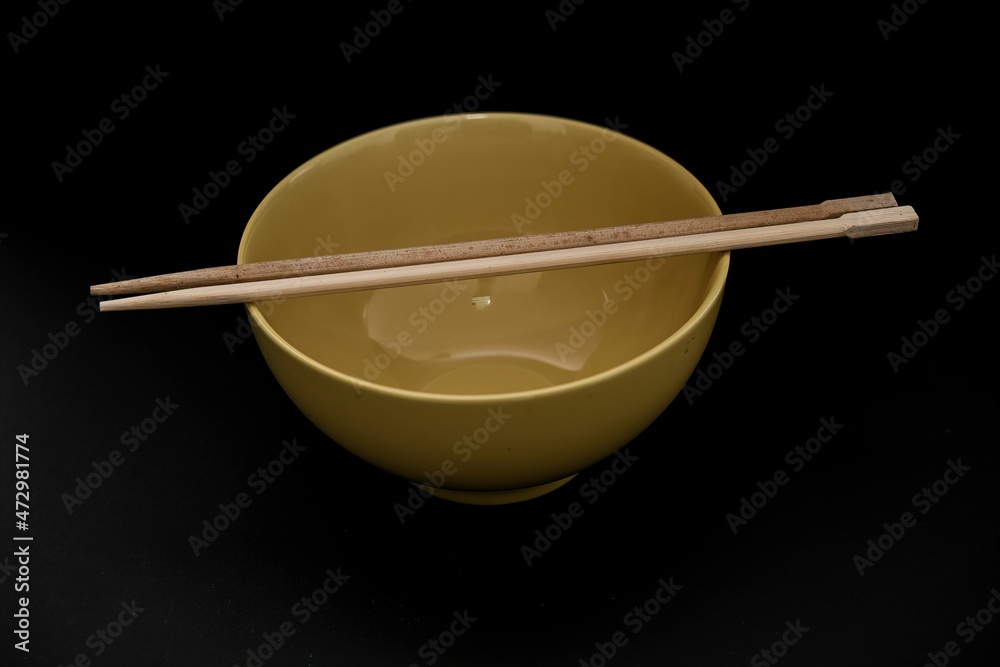 yellow porcelain rice bowl with wooden chopsticks on dark background yellow porcelain rice bowl with wooden chopsticks on dark background