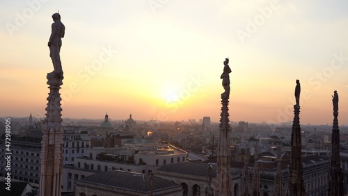 Europe , Italy , Milan December 2021 - 
the Madonnina of Duomo with its typical spiers, aerial view of the city skyline  at sunset