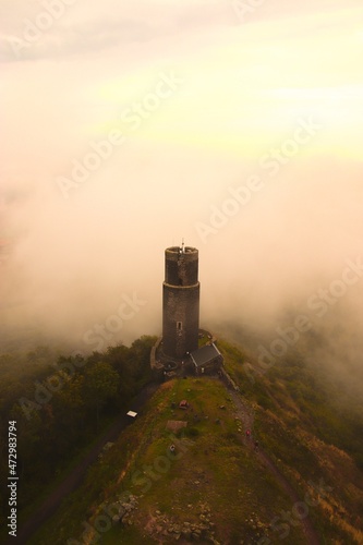 A view to the castle tower with morning fog and clouds around at Hazmburk, Czech republic