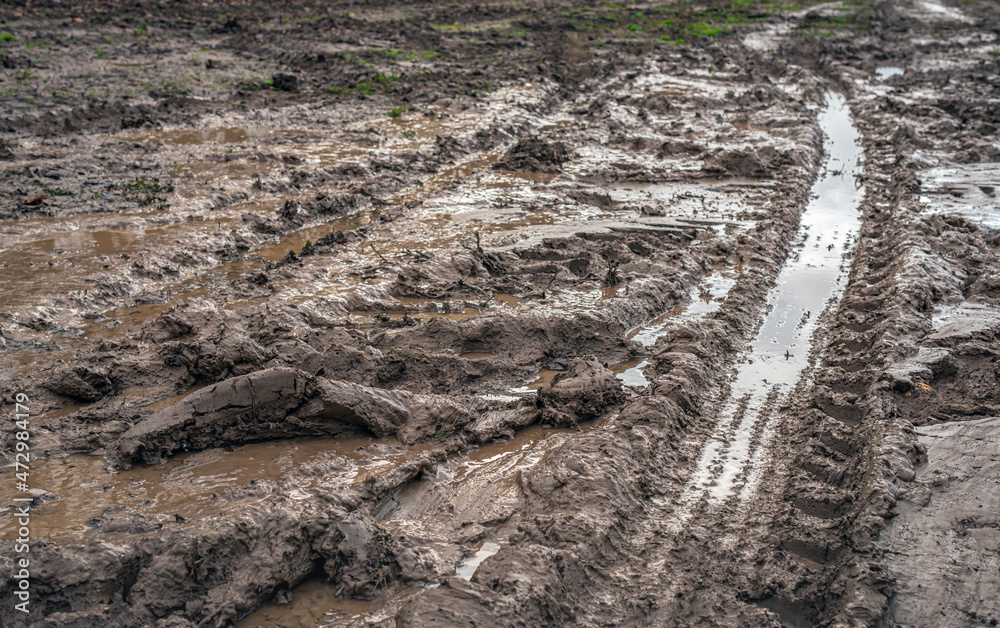 Wet clay field with wheel tracks and puddles of water. The photo was taken in the Dutch province of South Holland on a rainy day in the autumn season. Wet clay field with wheel tracks and puddles of water. The photo was taken in the Dutch province of South Holland on a rainy day in the autumn season.