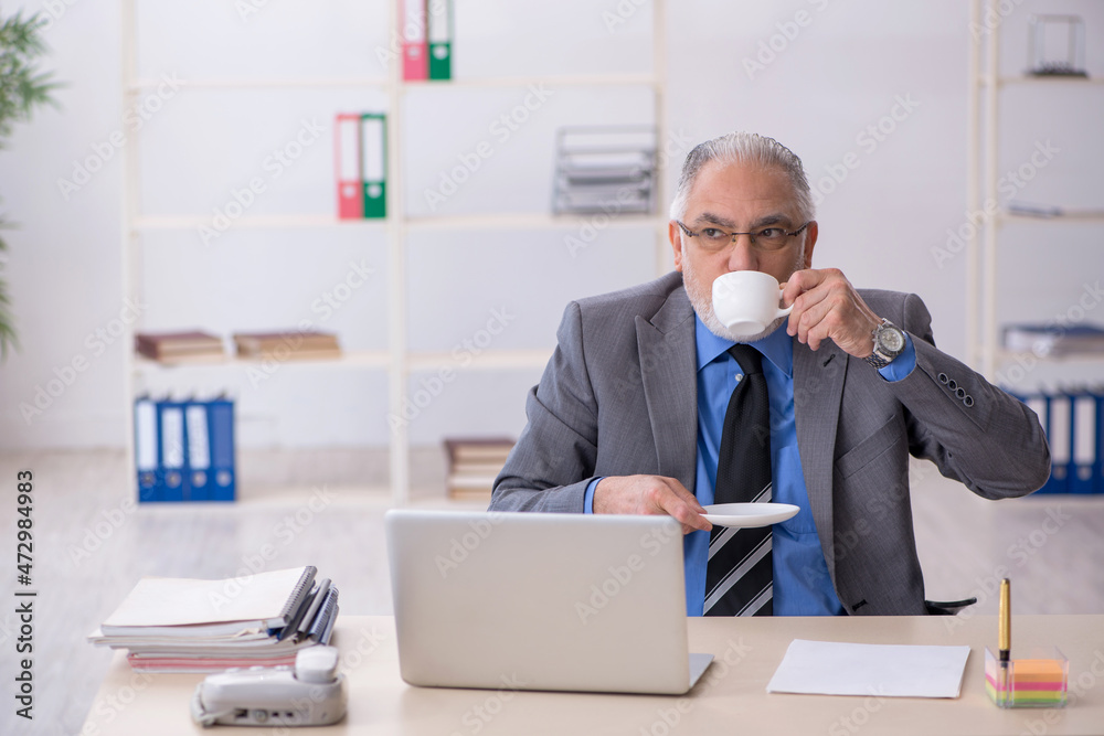 Old male employee drinking coffee during break Old male employee drinking coffee during break