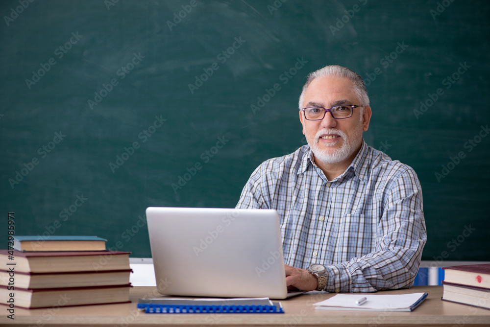 Old male teacher in the classroom Old male teacher in the classroom