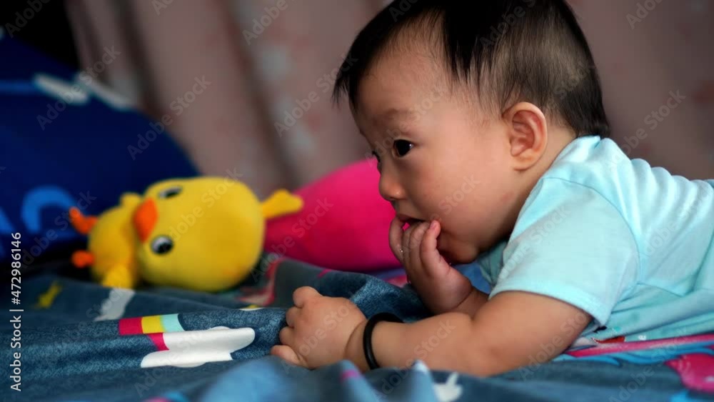 A baby smile lay at bed put the finger into mouth A baby smile lay at bed put the finger into mouth