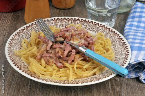 Linguine avec des lardons servis dans une assiette avec une fourchette photo