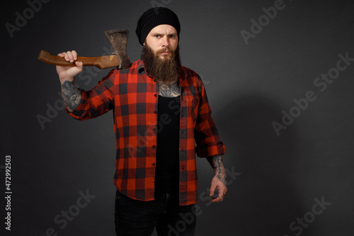 handsome man with long hair with an ax in his hands on a dark studio background