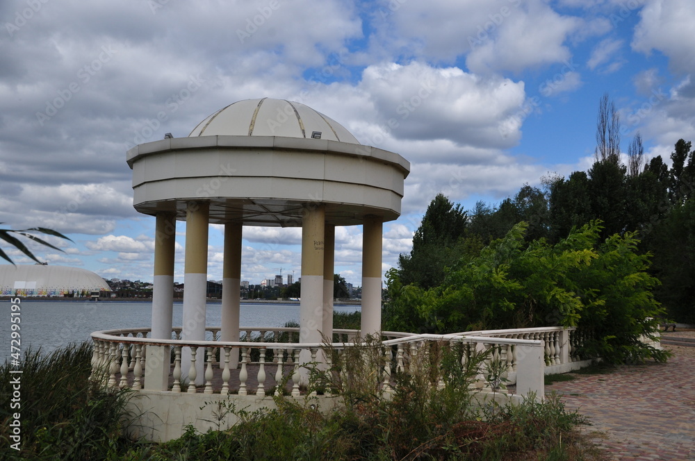 Small rotunda by the lake. Gazebo with stone parapet.