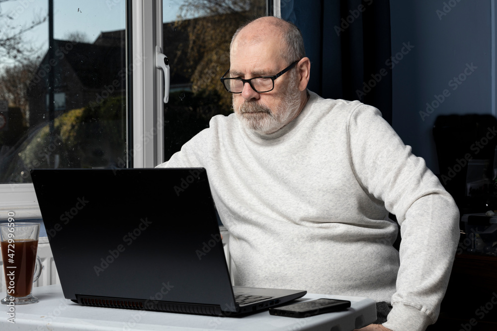 man working on a laptop from a home office. man working on a laptop from a home office.