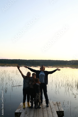 Mother and sons posing on wooden bridge by lake