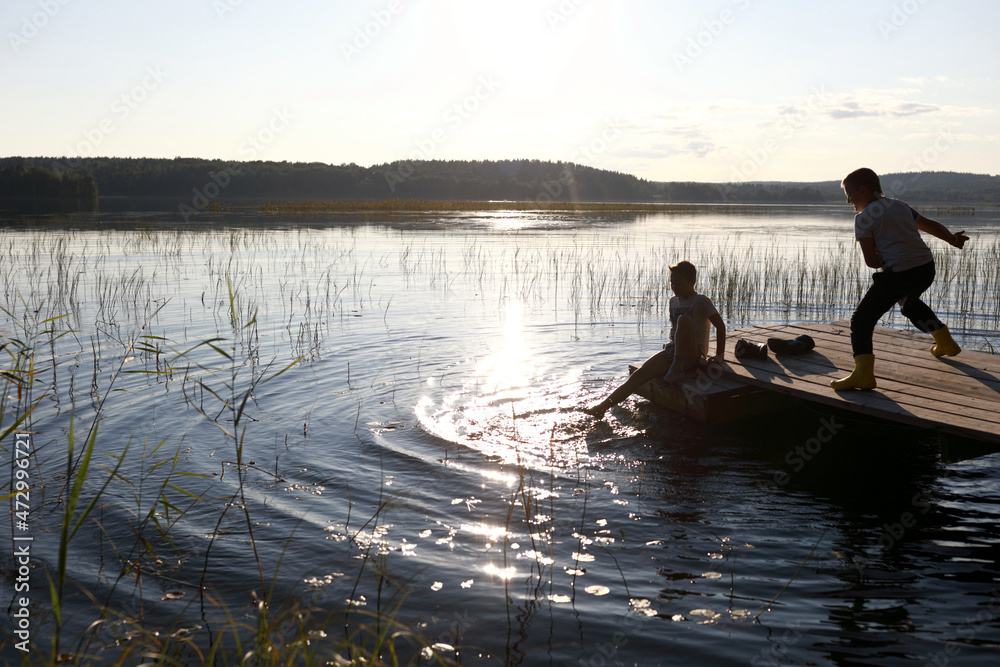 Children playing on wooden bridge by lake Children playing on wooden bridge by lake