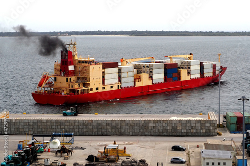 Exhaust smoke emissions from container ship docking at quayside port facilities.