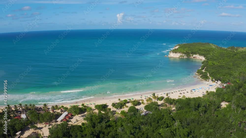 White sandy beach of Macau exotic peninsula in Dominican Republic from the air. The blue-turquoise sea water against the blue sky is a beautiful natural view. Caribbean for active sea travel. White sandy beach of Macau exotic peninsula in Dominican Republic from the air. The blue-turquoise sea water against the blue sky is a beautiful natural view. Caribbean for active sea travel.