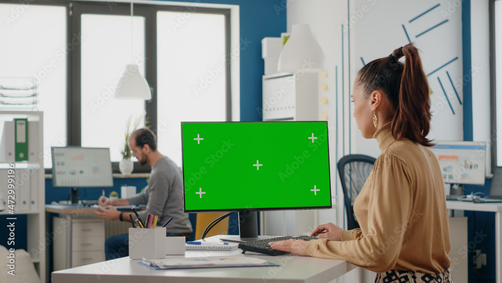 Woman working with isolated green screen on monitor at desk, looking at chroma key background with mock up template on display. Person using chroma-key on computer in business office Woman working with isolated green screen on monitor at desk, looking at chroma key background with mock up template on display. Person using chroma-key on computer in business office