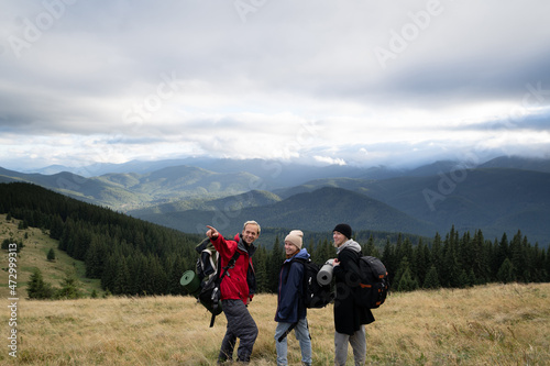 Hiking in the mountains, friends travelers looking forward, view of mountains and cloudy sky, people active lifestyle in the alps, mountain tourism