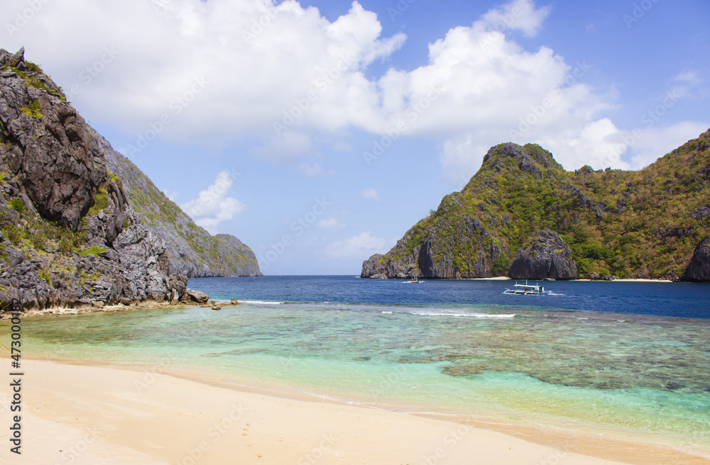 Tourist boat on sea with mountain isles on background. Philippines island with beach and rocky mountains. Tropical landscape. Scenic coastline with white sand and crystal water. Asian vacations. Tourist boat on sea with mountain isles on background. Philippines island with beach and rocky mountains. Tropical landscape. Scenic coastline with white sand and crystal water. Asian vacations.