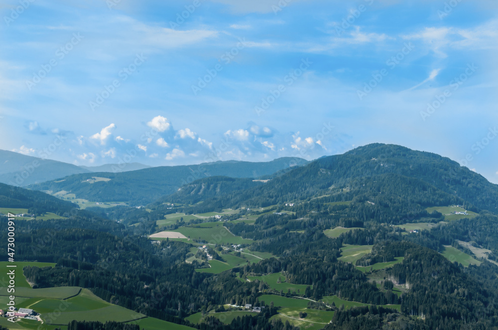 Bergige Landschaft in Österreich.  Blick von einem hochgelegenen Punkt auf  eine Gebirgskette. und einen kleinen Ort im Tal. Sonniger Herbsttag