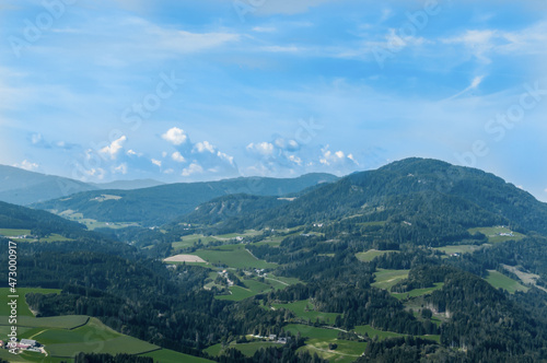 Bergige Landschaft in Österreich. Blick von einem hochgelegenen Punkt auf eine Gebirgskette. und einen kleinen Ort im Tal. Sonniger Herbsttag