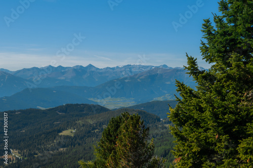 Bergige Landschaft in Österreich. Blick von einem hochgelegenen Punkt auf eine Gebirgskette im Vordergrund befinden sich Nadelbäume. Sonniger Herbsttag