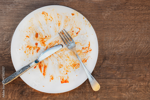 dirty plate after eating.  fork and knife on a plate. Dirty dish after eating.