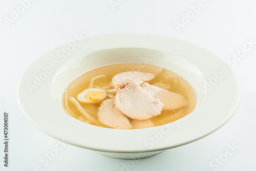 Classic Chicken broth with quail eggs and wheat noodles. Chicken soup stock served in white plate. First dish consomme isolated on white background
