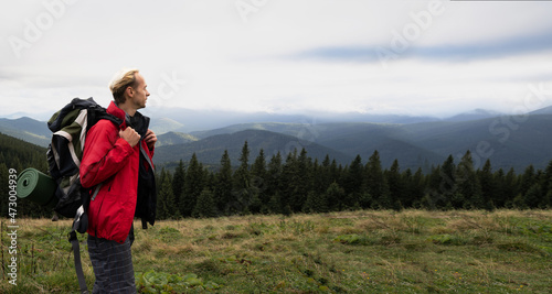 Mountain tourism, man traveler with backpack looking at the sky, Alps mountains background, hiking active lifestyle, adventure travel, banner