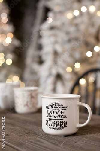 A cup of coffe with christmas tree lights bokeh as background. Holiday season coffee break.