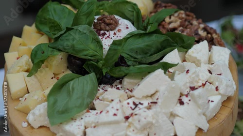 Yellow and white diced cheese with basil leaves on a wooden plate. Cheese cubes photo