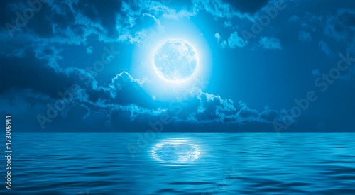 Night sky with full bright moon in the clouds  blue sea in the foreground  Elements of this image furnished by NASA 