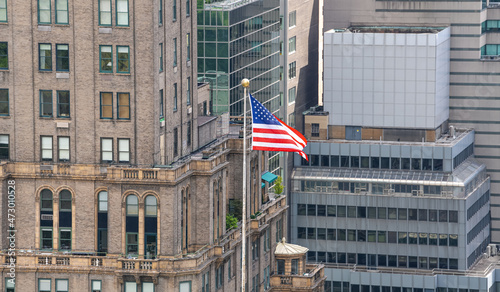 The national flag of United States of America winding between the tall skyscraper buildings from Manhattan, New York. Patriotism symbol..