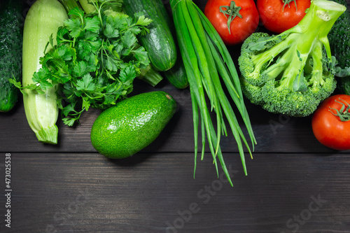 Fresh organic vegetables on a dark wooden background with space for text. Top view. Concept of healthy, vegetarian, diet food.