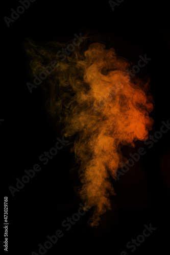 Fragment of orange magic curly steam smoke isolated on a black background, close-up. Create mystical photos.