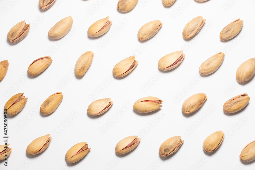 Obraz premium Roasted pistachio nuts pattern on white. Whole fried and dried pistachio nut