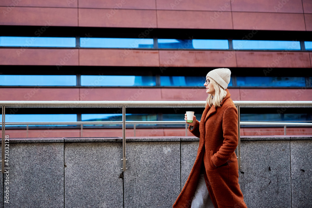 Young woman walking at city street with cup of coffee takeaway Young woman walking at city street with cup of coffee takeaway