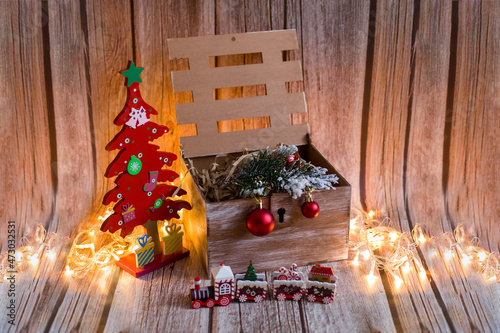 Wooden box with Christmas gifts. Christmas train with lights. Festive lights. The Christmas tree is red.