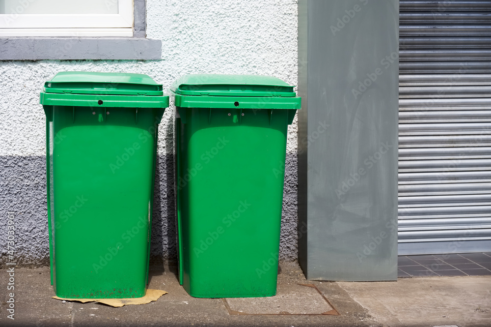 Green recycle wheelie bins in row for collection Green recycle wheelie bins in row for collection