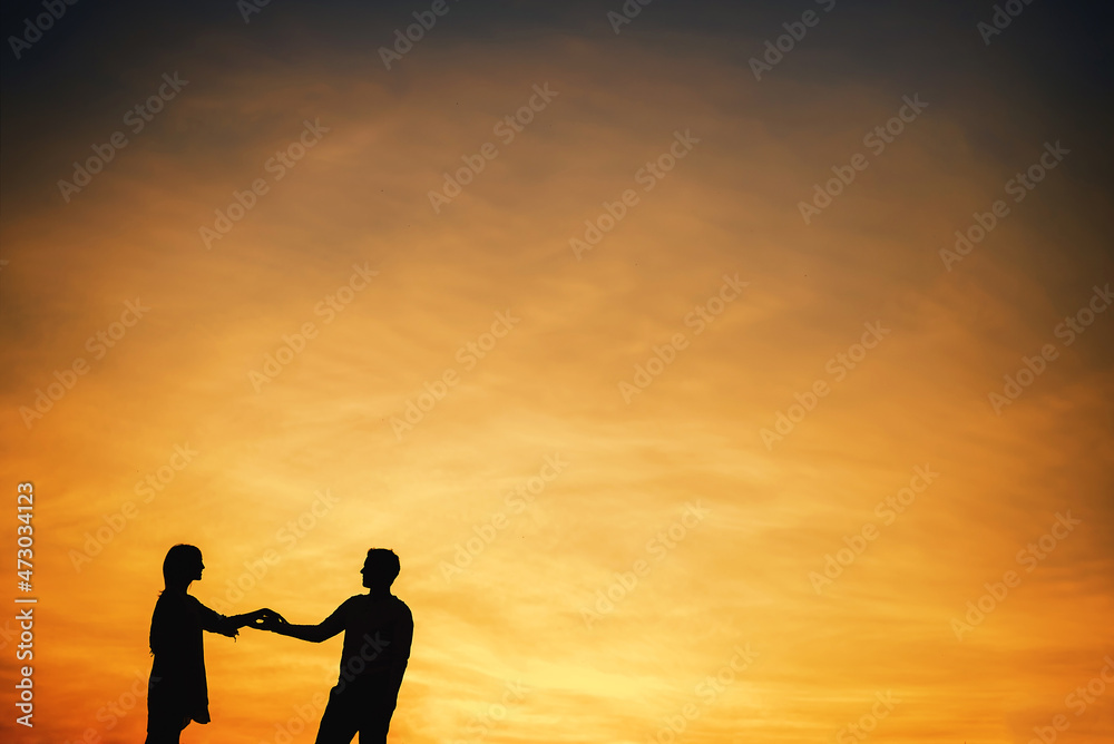 Silhouette of a couple in love against the sunset sky.
