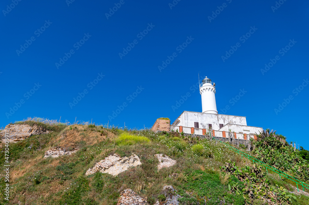 Lighthouse of Anzio, beautiful detail of the white structure on top of the hill next to the ruins of Nerones villa in summer, with blue sky. Rome Italy.