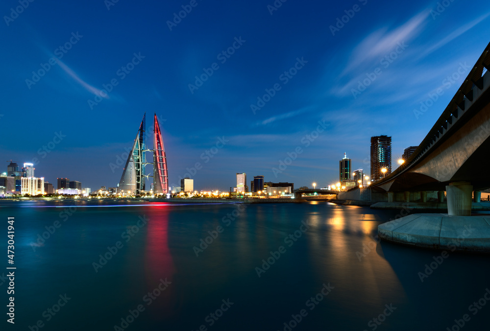 Skyline of Manama city dominated by Bahrain World trade Center building at night with Bahrain National Day theme light.