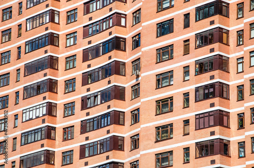 View of brick wall red contemporary apartment building with windows and balconies closeup