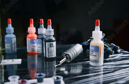 Few bottles of special paints for tattoos and tattooing a gun on the table