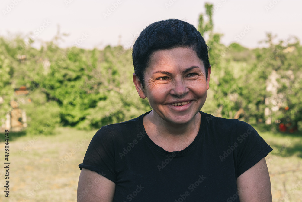 A middle-aged woman with black hair laughing outdoors. Happy Female person 54 years. A middle-aged woman with black hair laughing outdoors. Happy Female person 54 years.