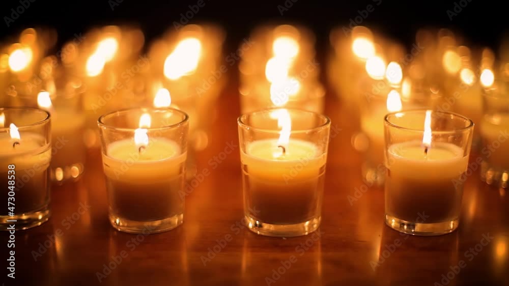 Camera moves past rows of glowing candles in a church or temple.