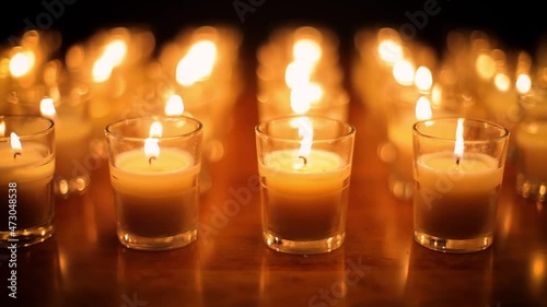Camera moves past rows of glowing candles in a church or temple. photo