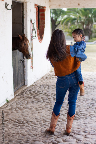 mother and daughter cowgirls in a barn