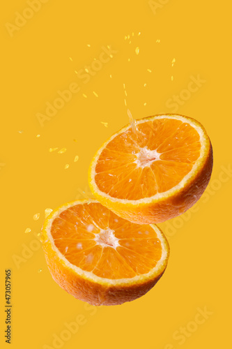 orange slices with drops of juice on a yellow background
