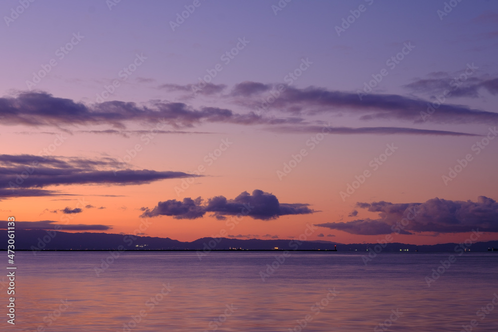 兵庫県芦屋市芦屋浜の夜明け。日の出とともに あたりはオレンジ色に染まる。大阪湾を隔てて大阪府の市街地と和泉山地がシルエットで浮かぶ