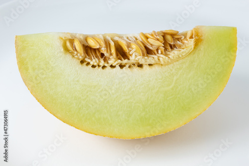 Ripe Gaul melon slice with seeds showing. Tropical fruit with white streaks on the yellow skin.